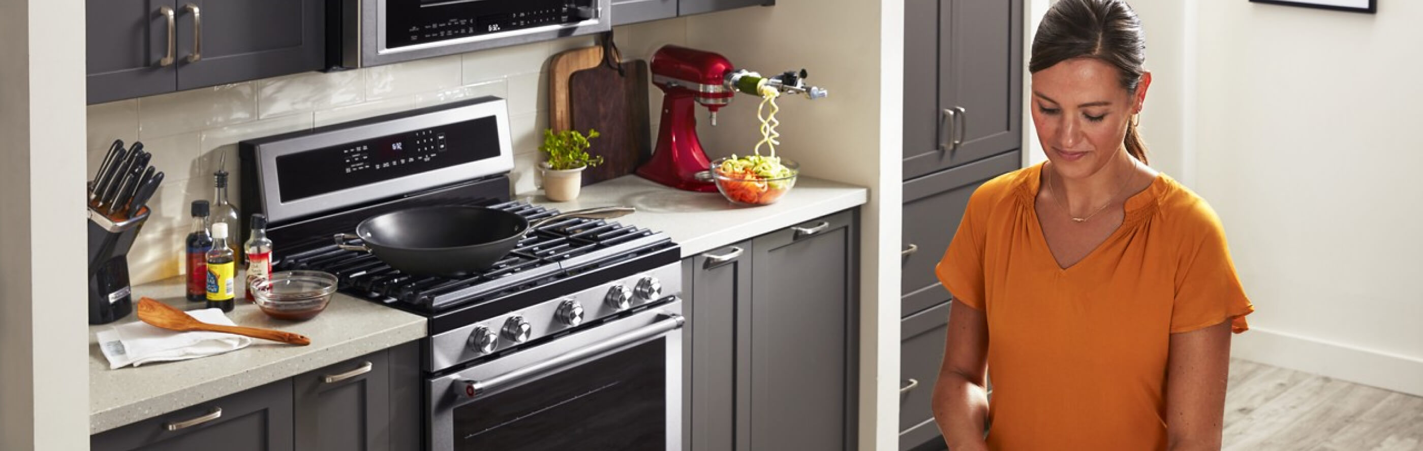 A person cooking in a kitchen with KitchenAid® appliances