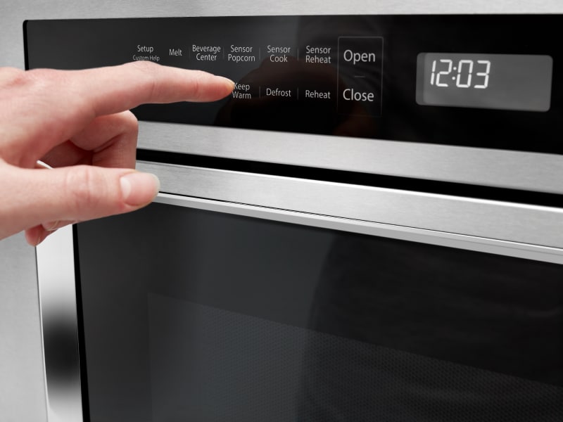 A person programming a setting on a KitchenAid® microwave.