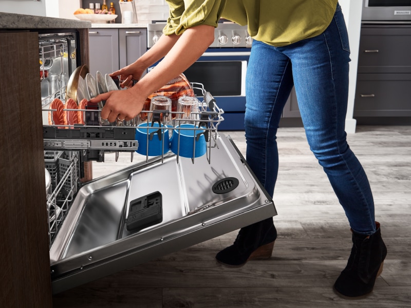 Person adjusting a dishwasher rack Person adjusting a dishwasher rack