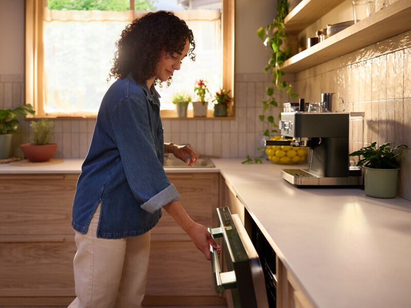 Woman in a modern kitchen opening a dishwasher