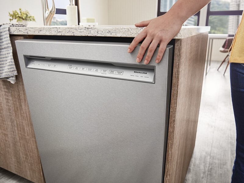 Person closing a front control dishwasher