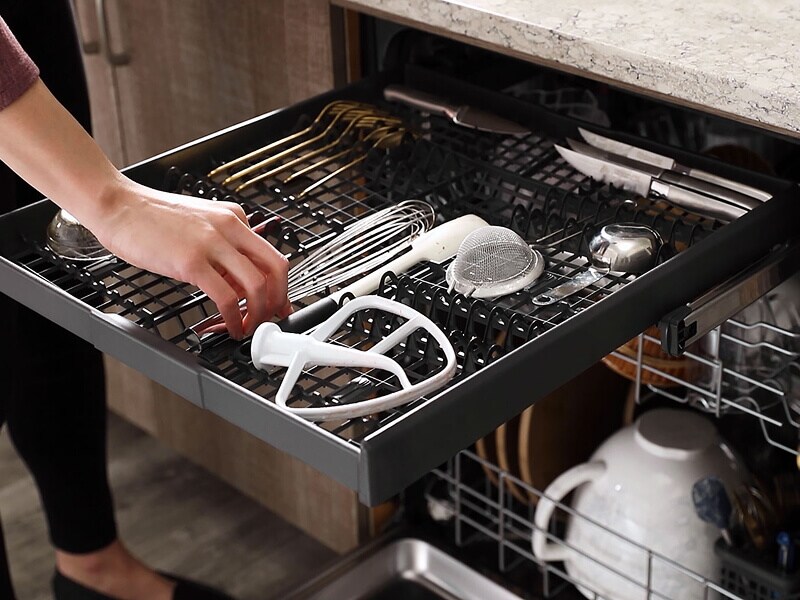  Person loading the third utensil rack in a dishwasher