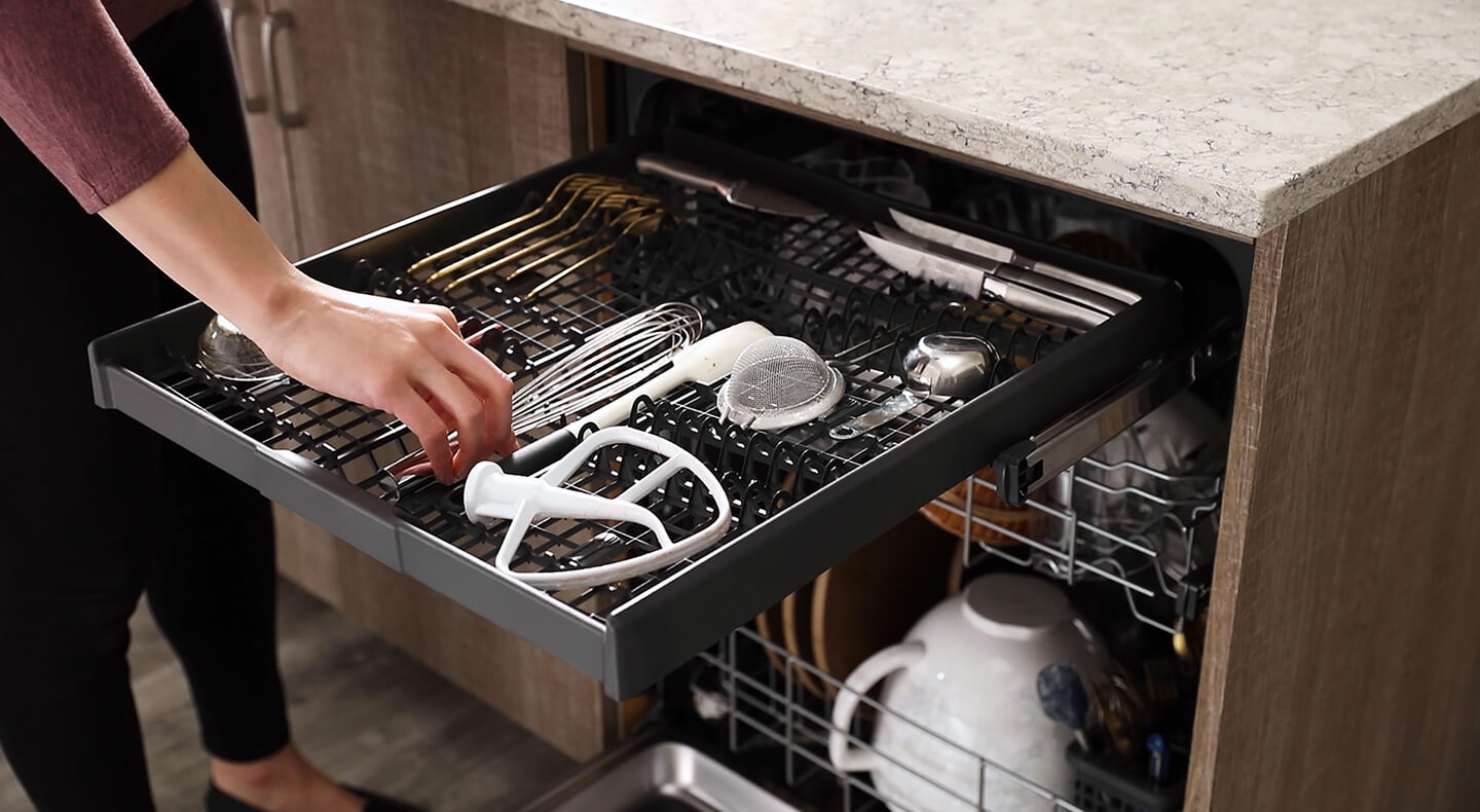  Person loading the third utensil rack in a dishwasher