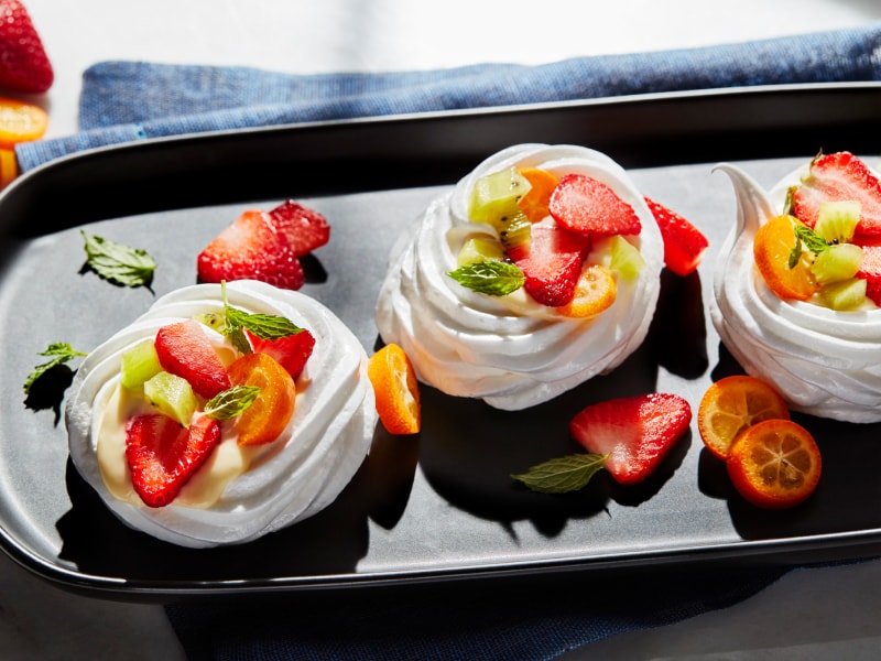 Mini pavlovas topped with sliced fruit Mini pavlovas topped with sliced fruit