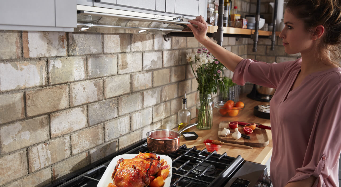 Person adjusting settings on an undercabinet hood