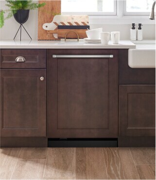 A KitchenAid® dishwasher surrounded by dark brown cabinets
