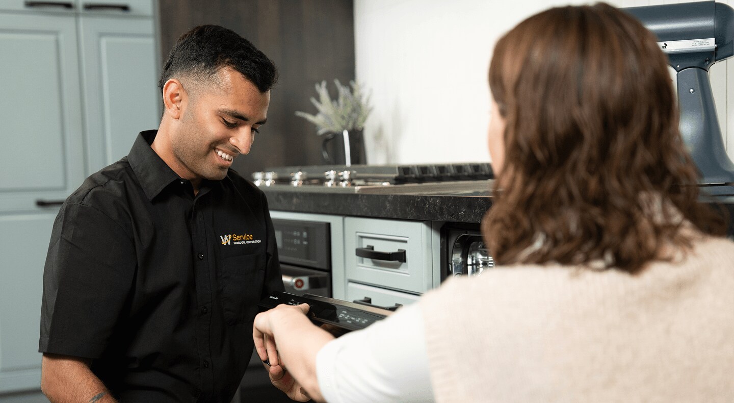 A technician helps a person in their kitchen A technician helps a person in their kitchen