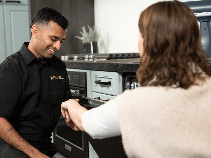 A technician helps a person in their kitchen A technician helps a person in their kitchen