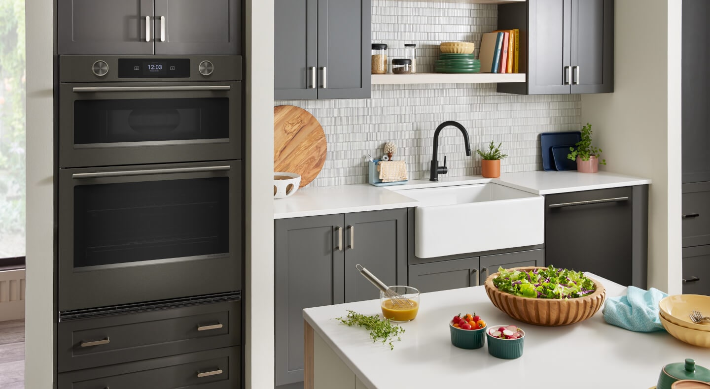 The inside of a kitchen with a sink and double wall oven in a modern finish