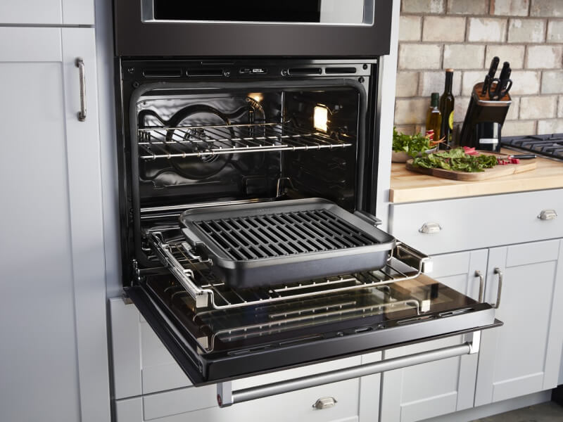 An open wall oven door exposing a roasting pan