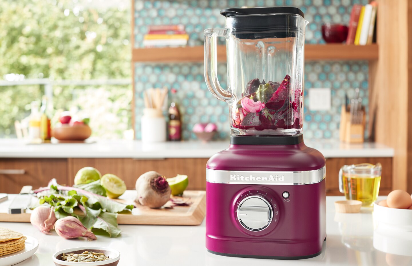 A KitchenAid® blender with fresh vegetables in a modern kitchen. A KitchenAid® blender with fresh vegetables in a modern kitchen.