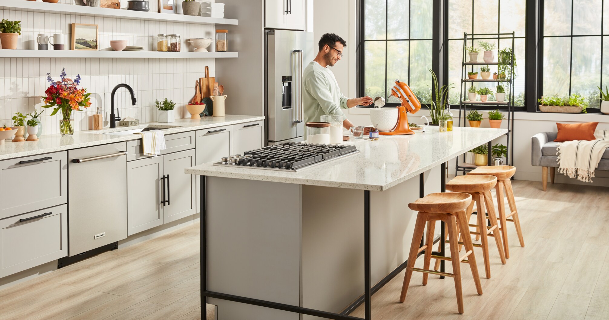 A man using a Honey KitchenAid® Stand Mixer on the island in a bright kitchen