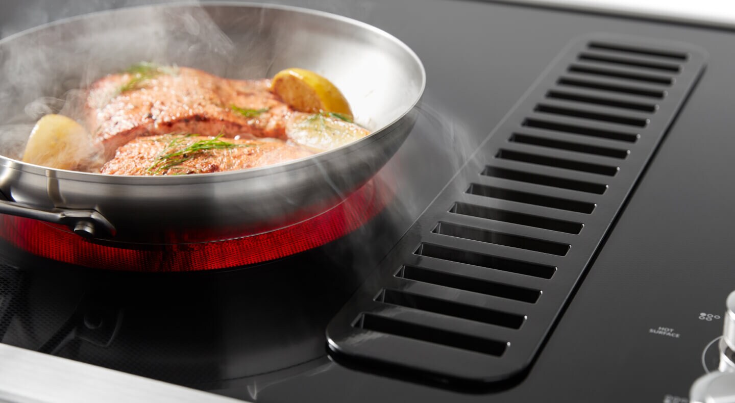Salmon cooking on a downdraft electric range with a lit up red element Salmon cooking on a downdraft electric range with a lit up red element