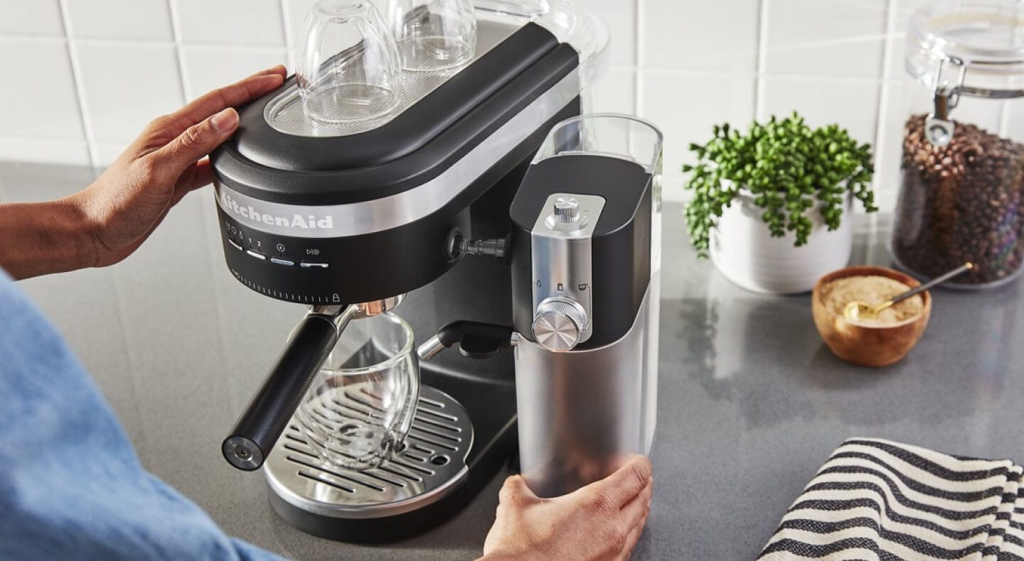 Person installing milk pitcher in black KitchenAid® Semi-Automatic Espresso Machine and Automatic Milk Frother Attachment