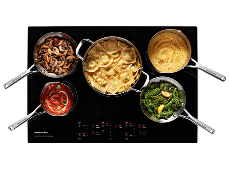 Overhead view of an induction cooktop surface with food Overhead view of an induction cooktop surface with food