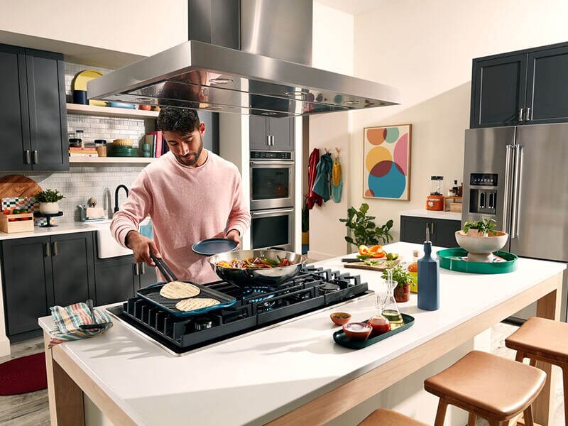 Person cooking on the griddle attachment of a gas stovetop Person cooking on the griddle attachment of a gas stovetop