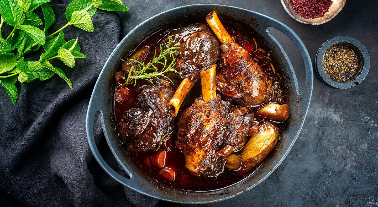 Lamb shanks braising inside of a Dutch oven
