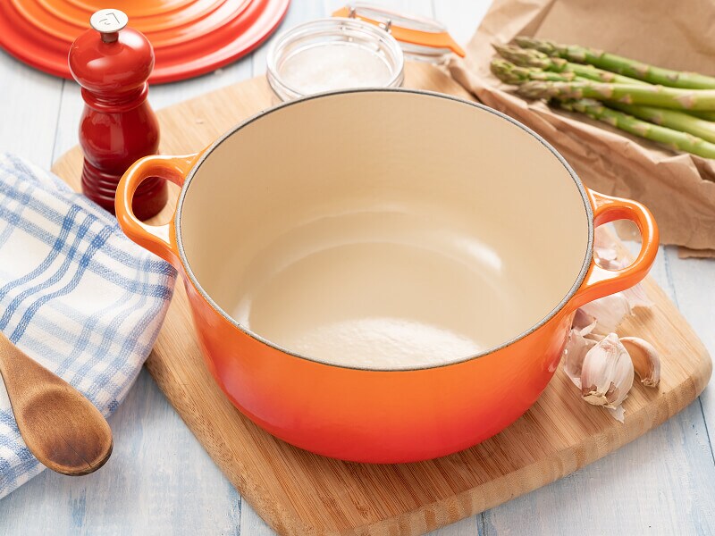 An orange Dutch oven surrounded by ingredients