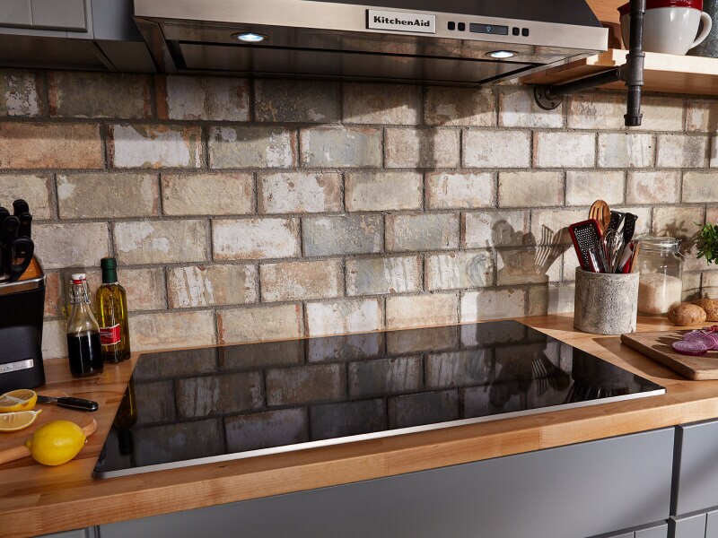 KitchenAid® range hood and cooktop with brick backsplash
