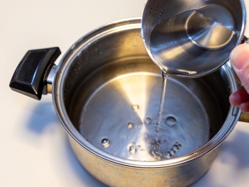 Alcohol being poured from a measuring cup into a saucepan