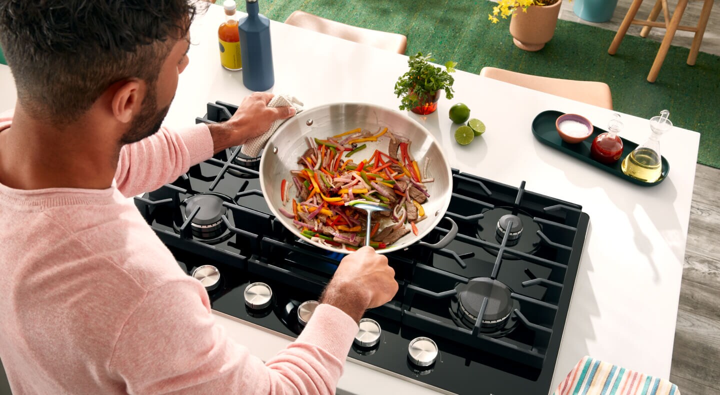 Person cooking food on KitchenAid® cooktop
