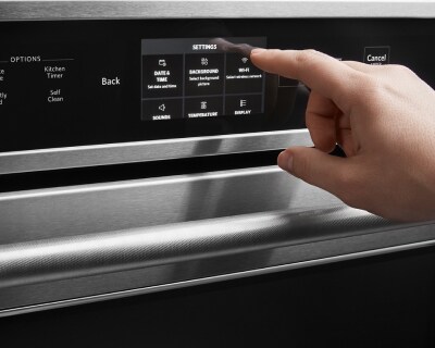 Hand adjusting settings on an oven’s control panel