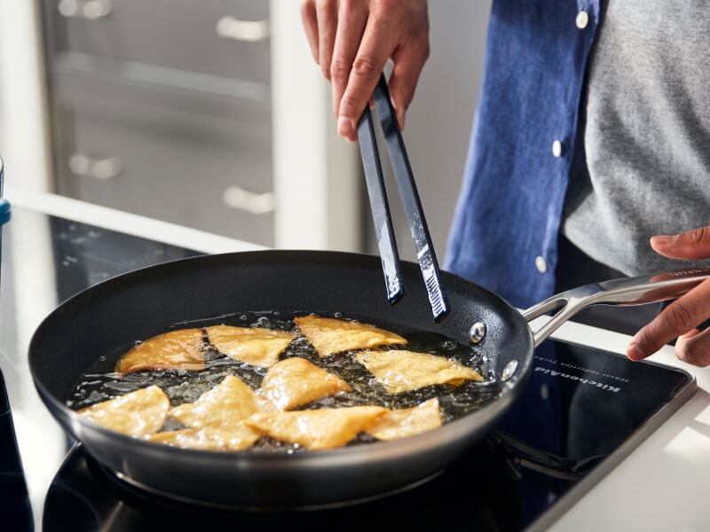 Someone frying food in a pan on their stovetop
