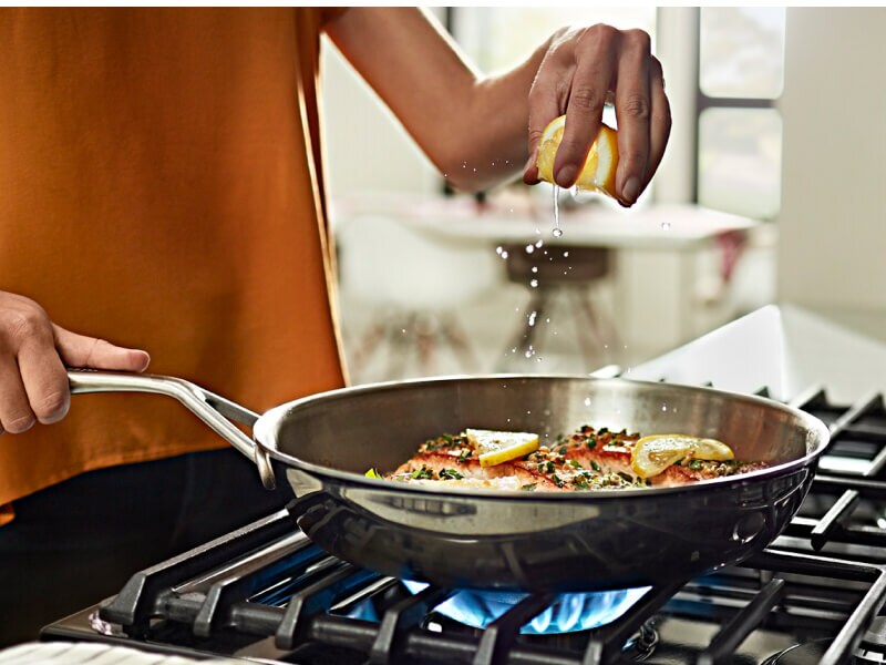 A person cooking food in a pan on a cooktop