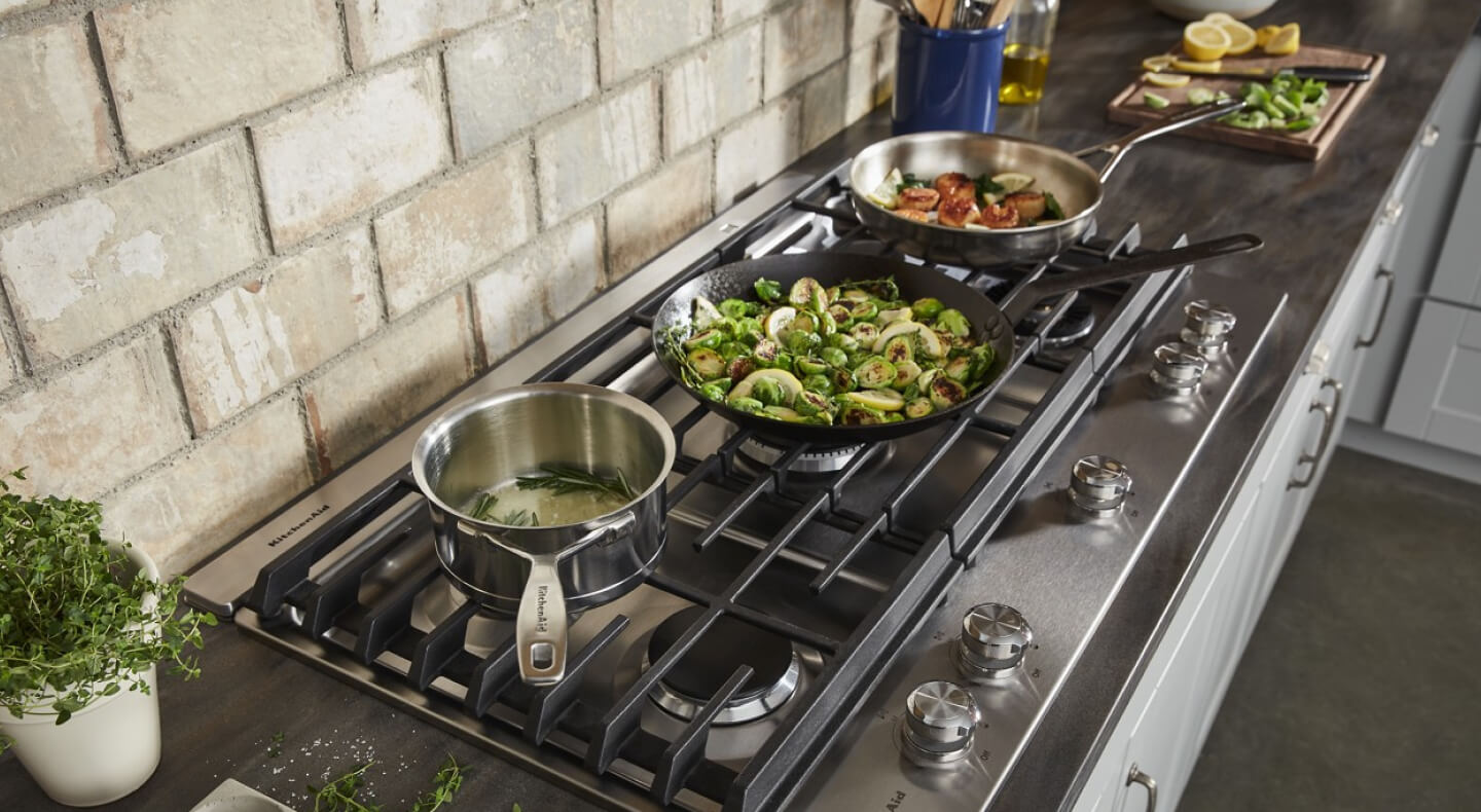 Pots and pans cooking various food, including vegetables, on a stovetop