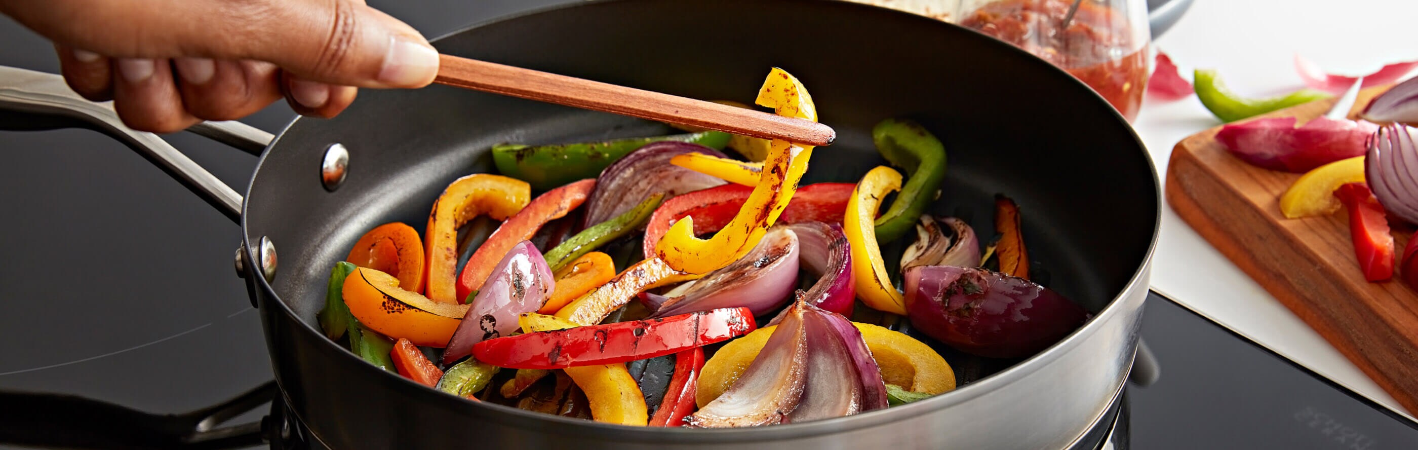 A person sauteing peppers in a pan