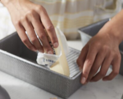 A person buttering a bread pan