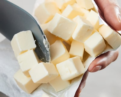 A person holding squares of butter and a rubber spatula