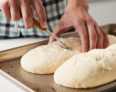 A man scoring raw bread loaves