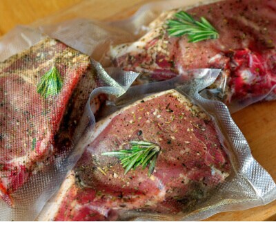 Three pieces of meat seasoned with rosemary in sous vide bags
