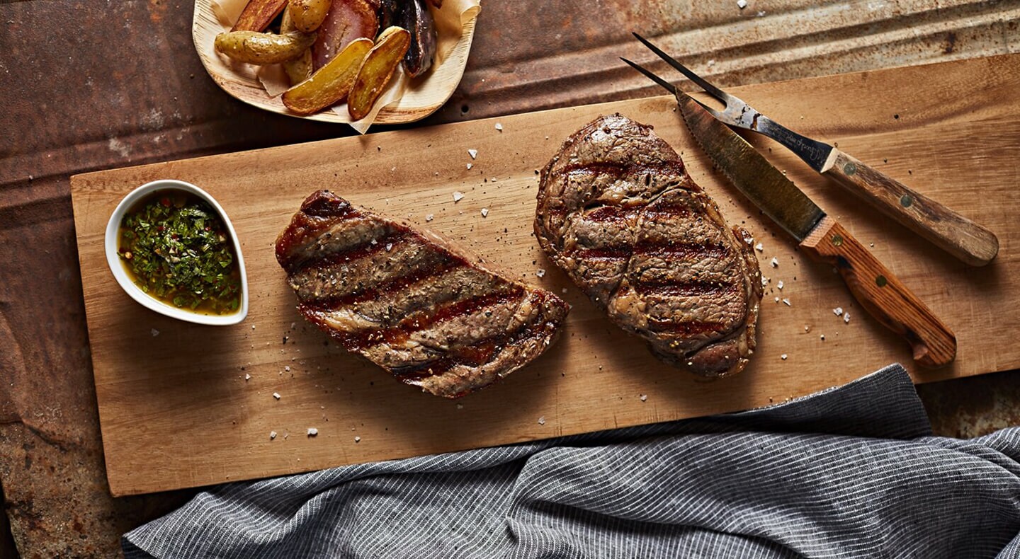 Two pieces of cooked steak on a cutting board Two pieces of cooked steak on a cutting board