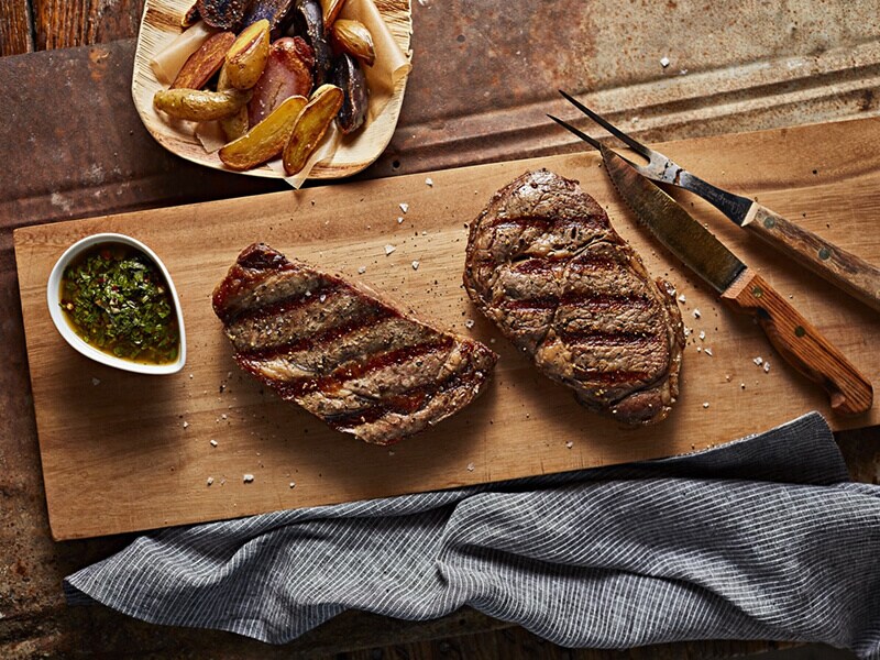Two pieces of cooked steak on a cutting board Two pieces of cooked steak on a cutting board