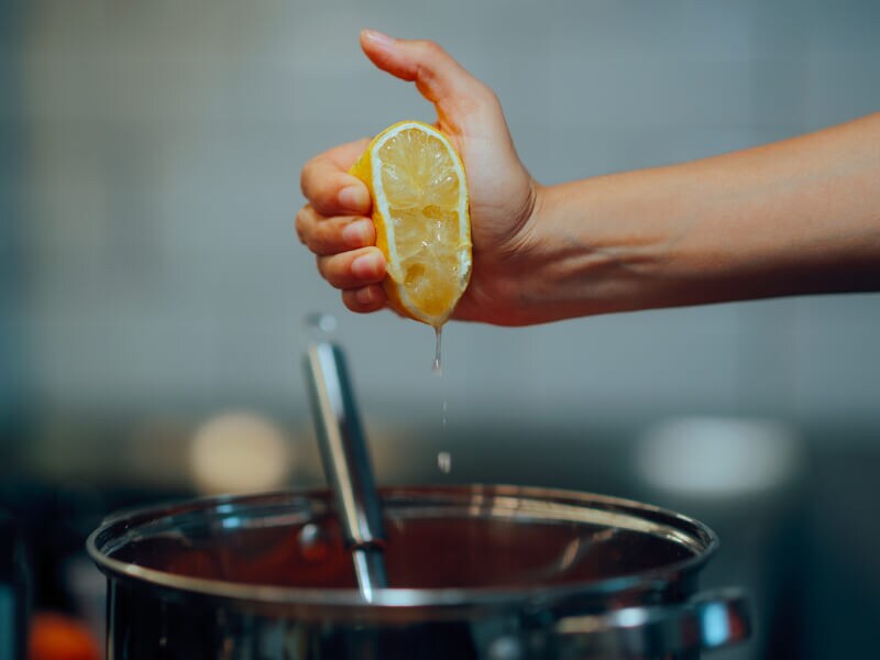 Someone squeezing a lemon over a pot
