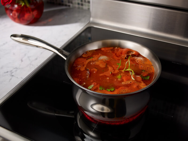 A pot filled with food cooking on a rangetop