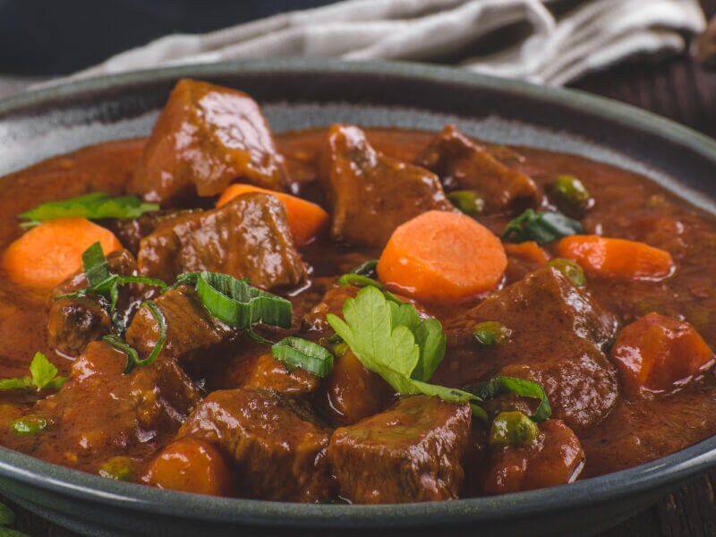 A bowl of stew with big chunks of meat and carrots