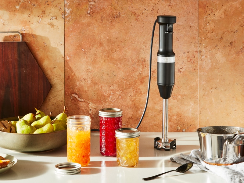 Black KitchenAid® hand blender next to jars of prepared jams