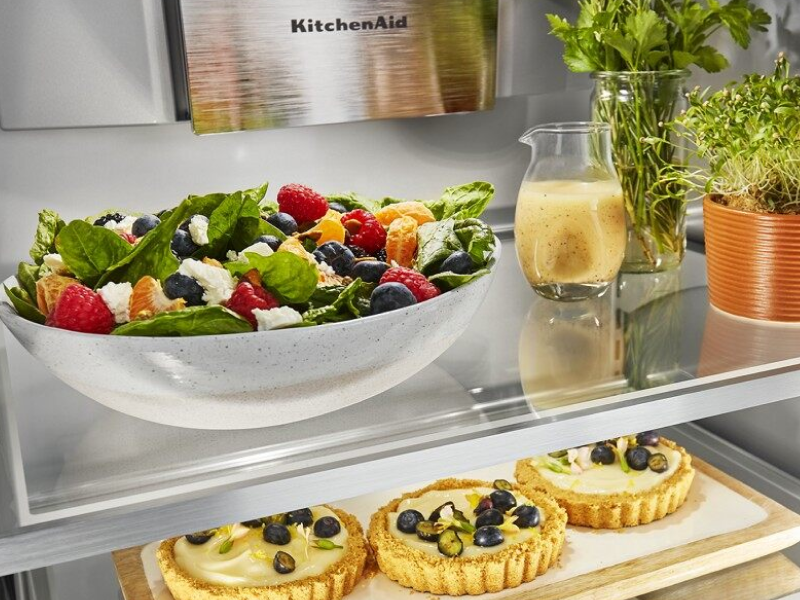Food platters, herbs and tarts in an open refrigerator Food platters, herbs and tarts in an open refrigerator