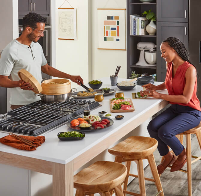 A man and woman cooking together at a kitchen island