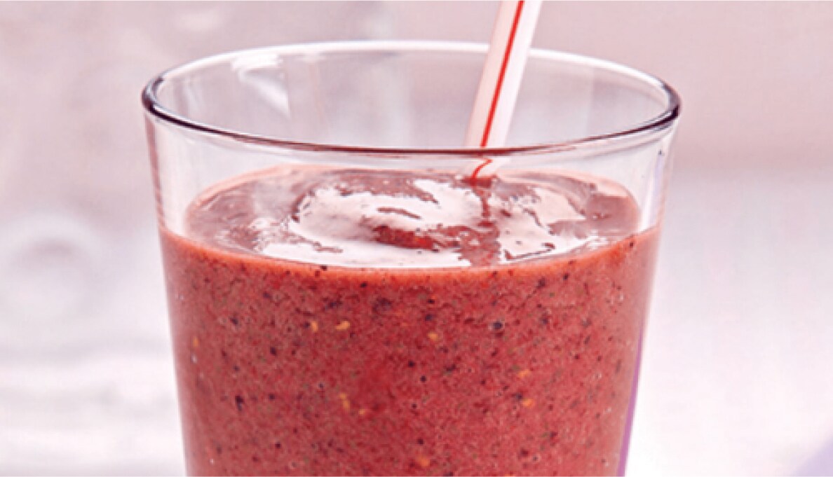 A red fruit smoothie in a glass.
