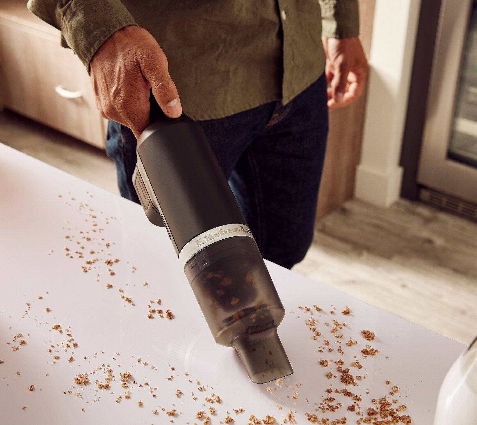 A person using the KitchenAid Go™ Cordless Kitchen Vacuum to pick up crumbs on a countertop.