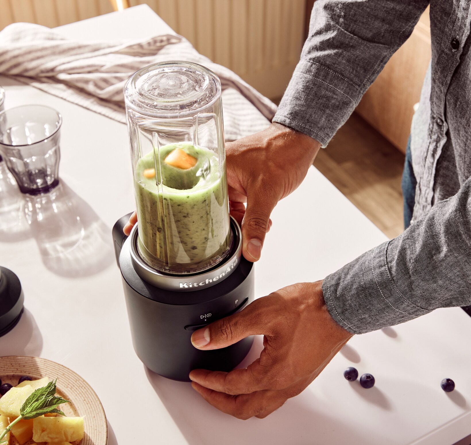 A person using the KitchenAid Go™ Cordless Personal Blender to blend a green smoothie.