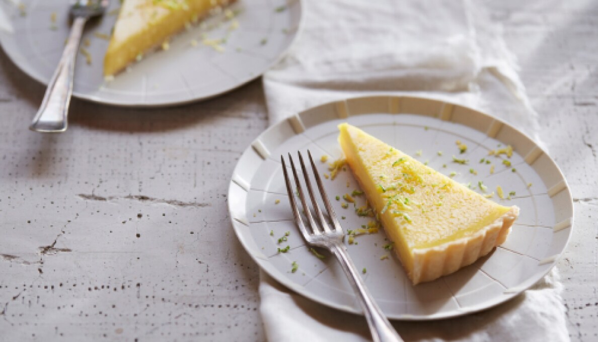 A slice of key lime pie on a white plate with a fork.