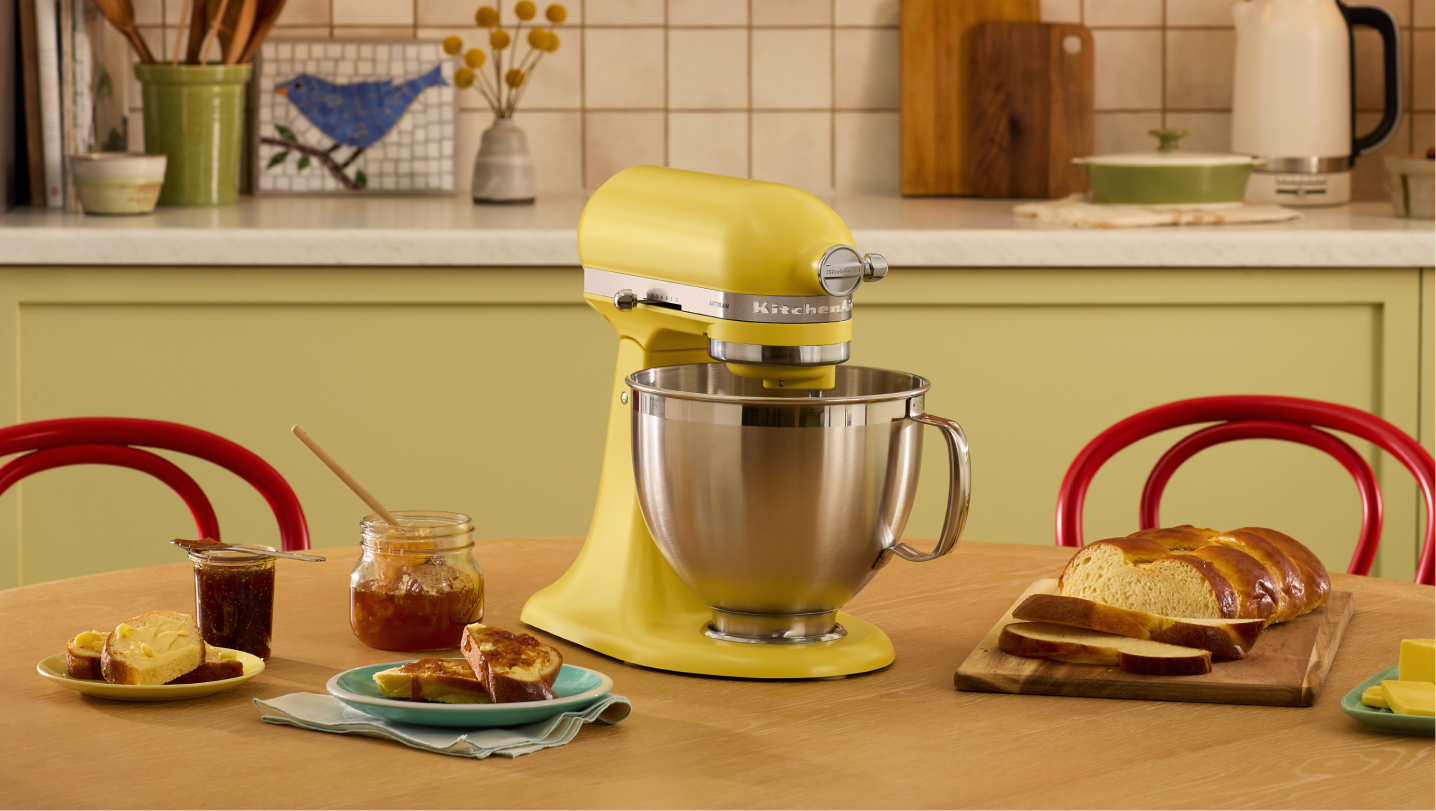 A KitchenAid Butter Stand Mixer surrounded by various jams, breads and butter.