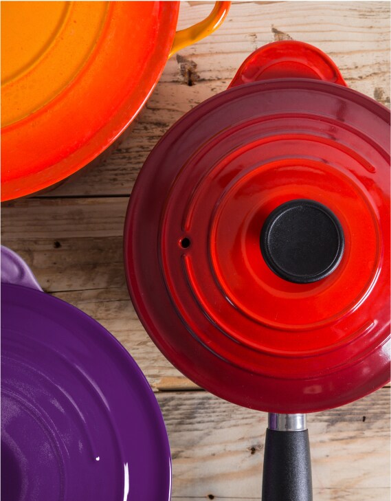 A set of three sauce pans in rich jewel-toned red, orange and purple