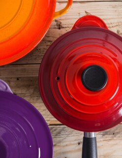 A set of three sauce pans in rich jewel-toned red, orange and purple