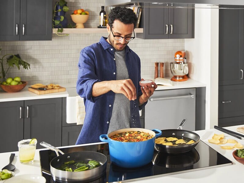 A person salting their food atop an induction cooktop